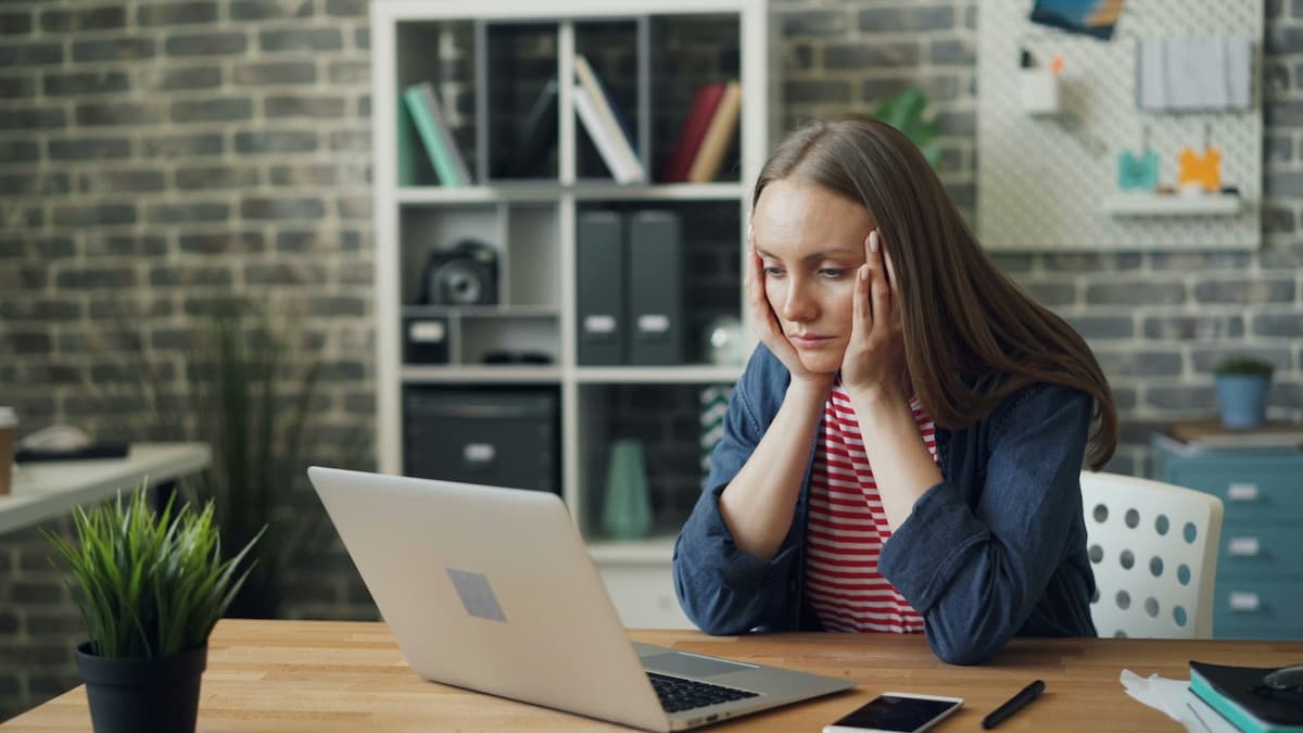 Frau sitzt nachdenkend am Laptop